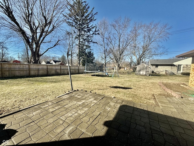 view of patio with a trampoline, a playground, and a fenced backyard