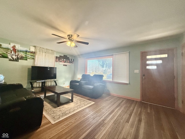 living area featuring hardwood / wood-style flooring, baseboards, and a ceiling fan