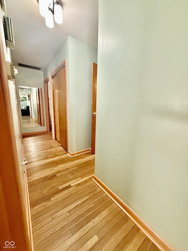 hall featuring light wood-type flooring and baseboards