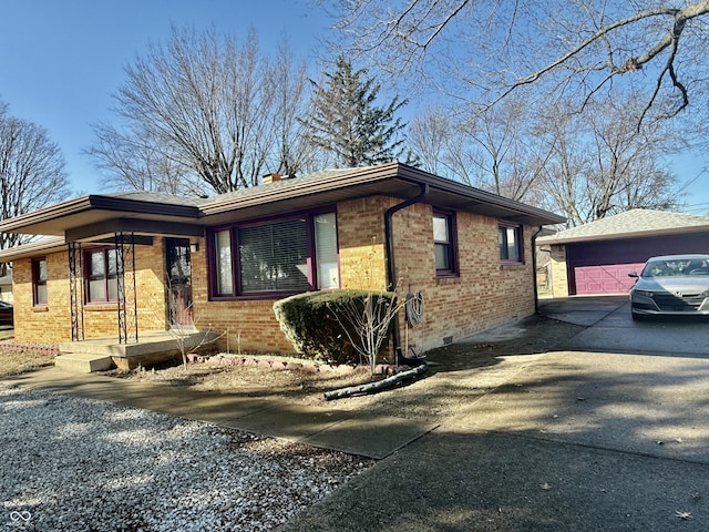 view of side of home with crawl space, a garage, an outdoor structure, and brick siding