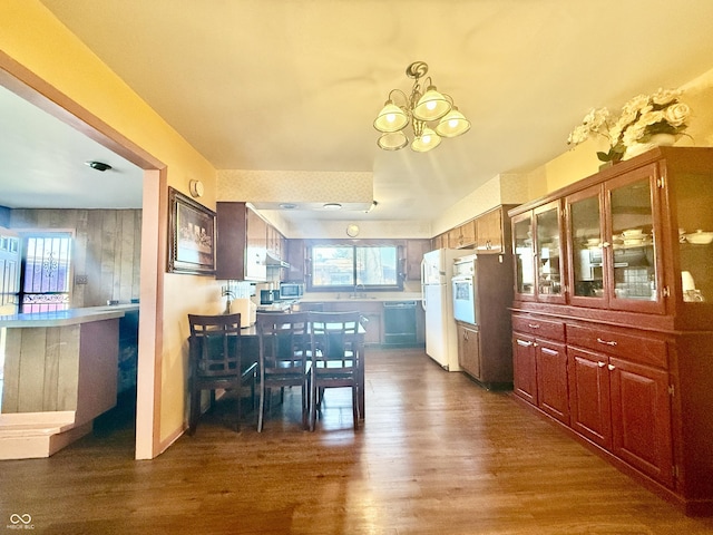 kitchen with under cabinet range hood, light countertops, freestanding refrigerator, dark wood finished floors, and an inviting chandelier