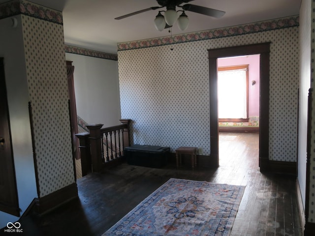 interior space with wallpapered walls, a ceiling fan, and wood finished floors