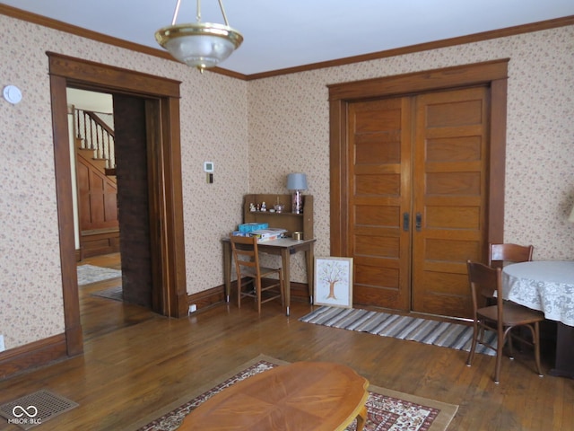 dining space with wood finished floors, crown molding, baseboards, and wallpapered walls