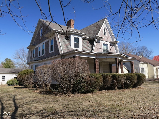 view of side of property featuring a shingled roof, a chimney, and brick siding