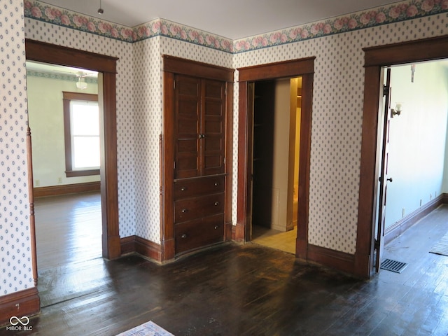 interior space featuring baseboards, hardwood / wood-style floors, visible vents, and wallpapered walls