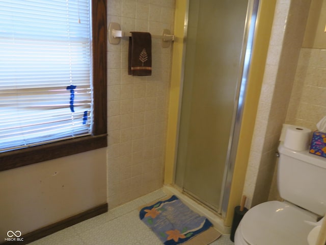 full bathroom with a stall shower, tile walls, and toilet