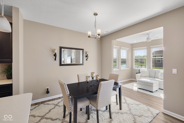 dining area with light wood-style floors, baseboards, and an inviting chandelier