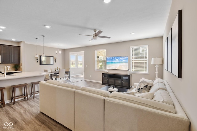 living area featuring baseboards, recessed lighting, a ceiling fan, and light wood-style floors