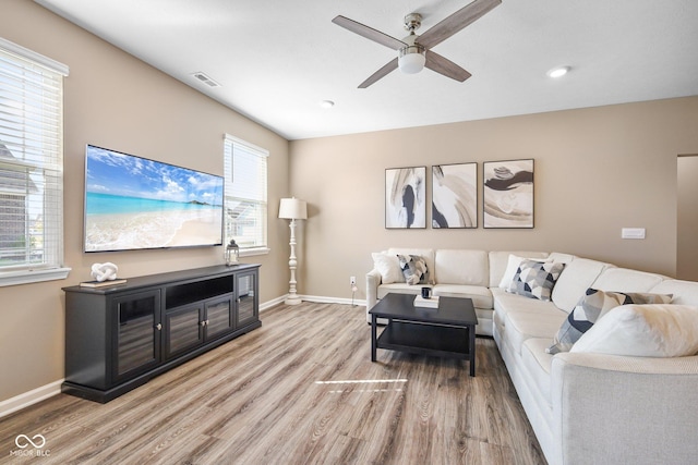 living area featuring light wood-style floors, visible vents, ceiling fan, and baseboards