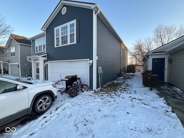 snow covered property featuring an attached garage