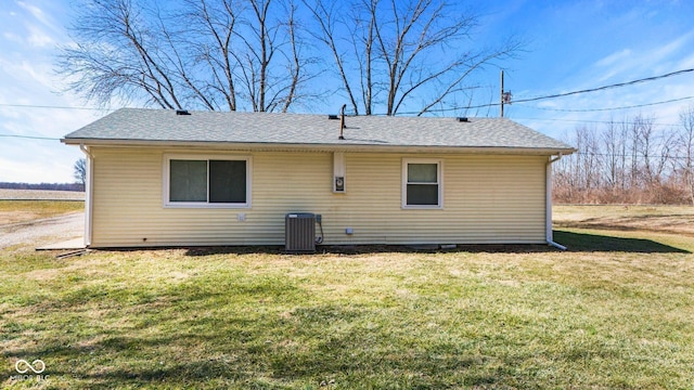 back of house with roof with shingles, a yard, and central AC unit