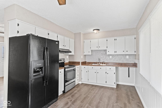 kitchen featuring stainless steel electric stove, black refrigerator with ice dispenser, under cabinet range hood, white cabinetry, and a sink