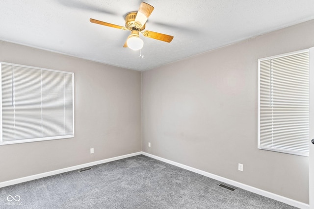 spare room with carpet, visible vents, and baseboards