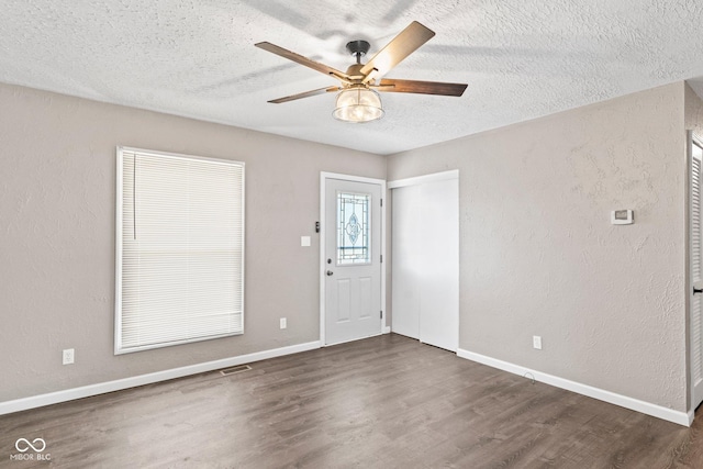 foyer entrance with dark wood finished floors, visible vents, a textured wall, a textured ceiling, and baseboards