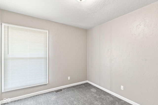 unfurnished room with carpet, visible vents, a textured wall, and a textured ceiling