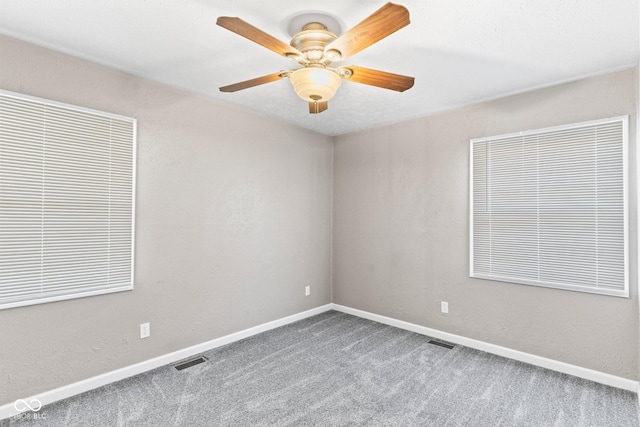 unfurnished room with carpet floors, baseboards, visible vents, and a ceiling fan