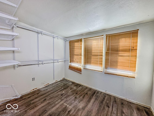 empty room with dark wood finished floors and a textured ceiling