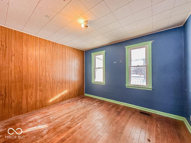 unfurnished room featuring wood-type flooring, visible vents, and baseboards