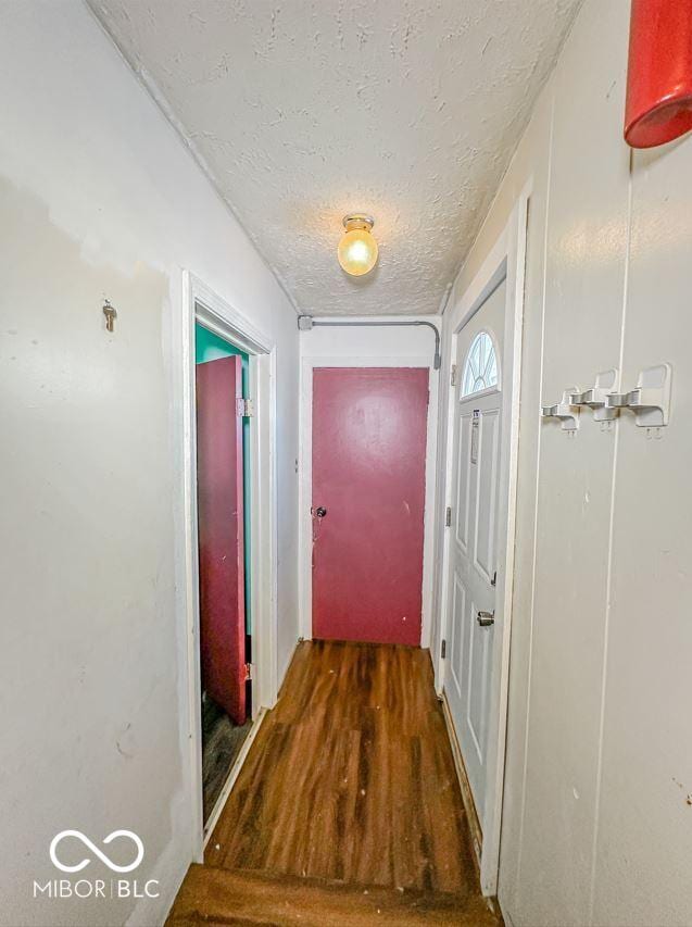 corridor with a textured ceiling and dark wood finished floors