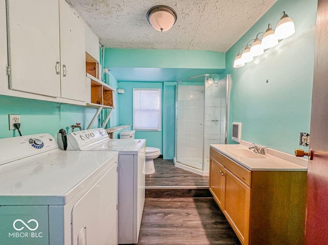 washroom with a textured ceiling, laundry area, dark wood-style flooring, a sink, and washer and clothes dryer