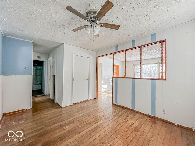 empty room with a textured ceiling, ceiling fan, and hardwood / wood-style flooring