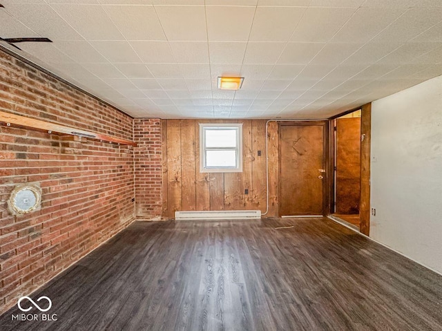 spare room featuring brick wall, a baseboard radiator, and dark wood finished floors