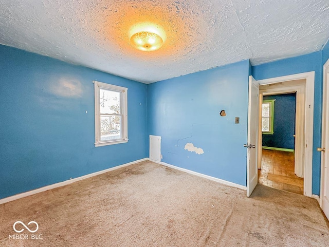 carpeted spare room with a textured ceiling and baseboards