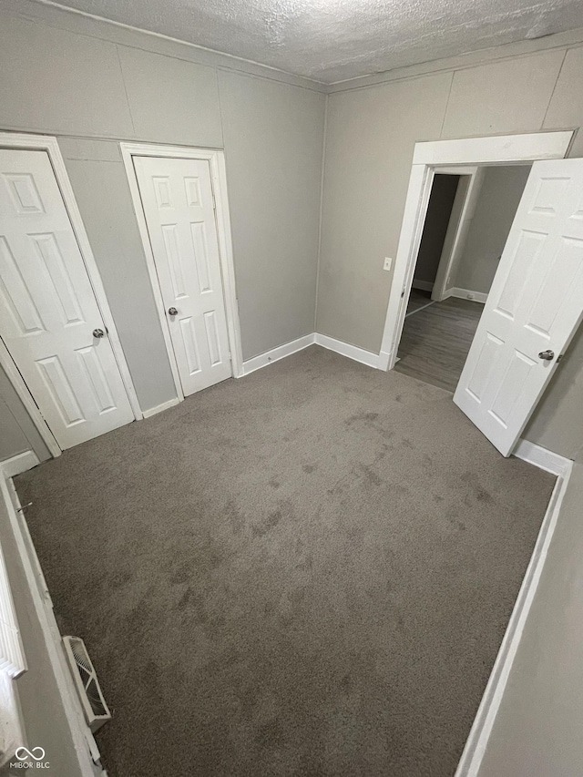 unfurnished bedroom with a textured ceiling, ornamental molding, carpet flooring, and visible vents