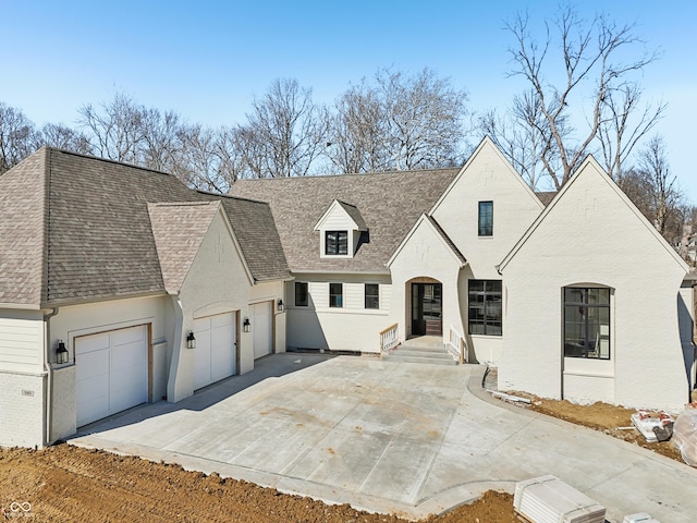 view of front of home with a garage, concrete driveway, brick siding, and a shingled roof