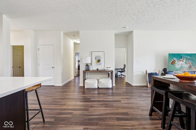 dining area featuring dark wood-style floors, a textured ceiling, and baseboards