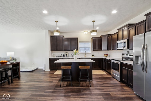 kitchen featuring dark wood finished floors, appliances with stainless steel finishes, dark brown cabinets, and a sink