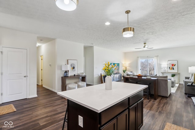 kitchen with a textured ceiling, open floor plan, dark wood finished floors, and light countertops