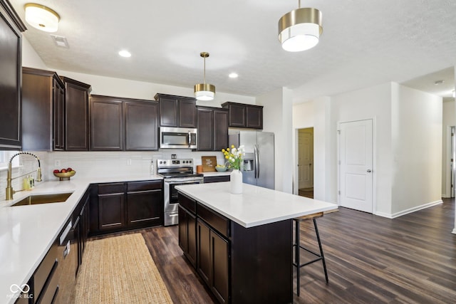 kitchen featuring tasteful backsplash, dark wood-style floors, stainless steel appliances, a kitchen bar, and a sink