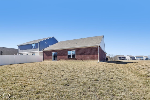 rear view of property with a yard, fence, and brick siding