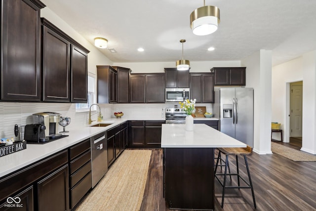 kitchen with a breakfast bar, decorative backsplash, appliances with stainless steel finishes, a sink, and dark brown cabinetry