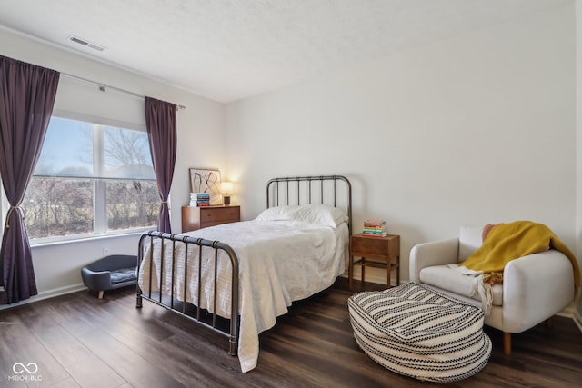 bedroom featuring wood finished floors, visible vents, and baseboards