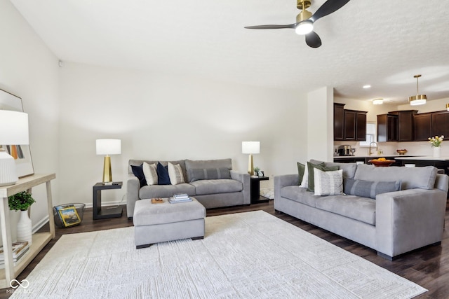 living area with a textured ceiling, dark wood finished floors, and a ceiling fan