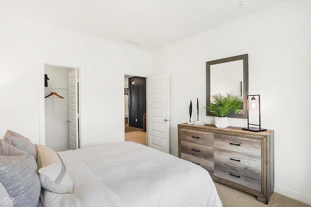 bedroom featuring light colored carpet, visible vents, and a spacious closet