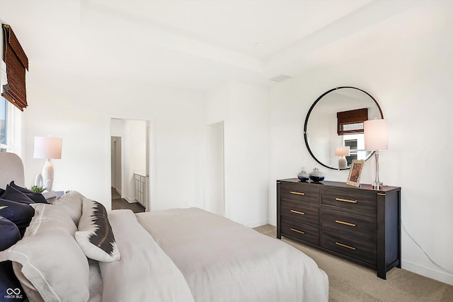 bedroom with light carpet, a raised ceiling, visible vents, and baseboards