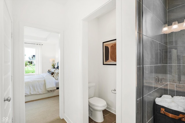 ensuite bathroom with a tile shower, ensuite bath, toilet, and baseboards