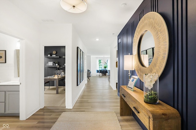 hall featuring light wood-style floors, baseboards, and recessed lighting