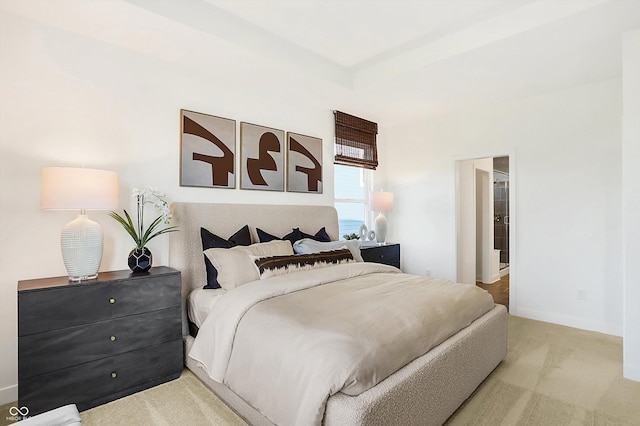 bedroom with a tray ceiling, baseboards, and carpet flooring