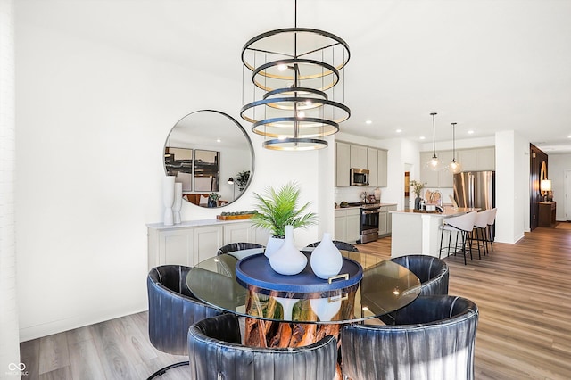 dining area with light wood-style floors, recessed lighting, and a notable chandelier