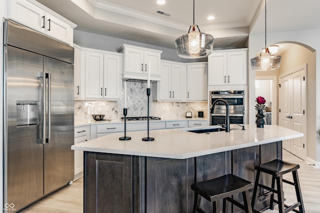 kitchen with arched walkways, stainless steel appliances, visible vents, white cabinetry, and crown molding