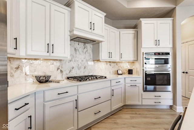 kitchen featuring light countertops, appliances with stainless steel finishes, white cabinetry, and decorative backsplash