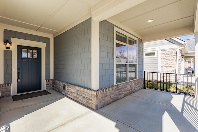 entrance to property featuring stone siding and a porch