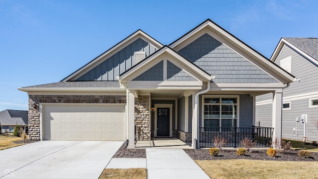 view of front of property featuring driveway, stone siding, an attached garage, covered porch, and board and batten siding