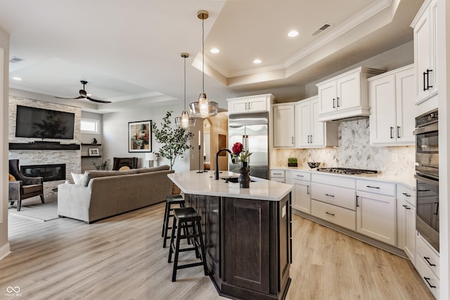 kitchen with visible vents, appliances with stainless steel finishes, a tray ceiling, light countertops, and a fireplace