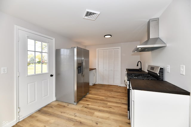 kitchen featuring wall chimney exhaust hood, appliances with stainless steel finishes, light wood-style flooring, and visible vents