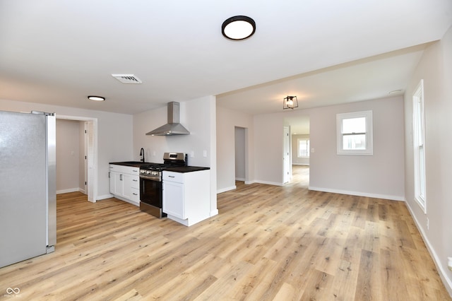 kitchen with visible vents, dark countertops, wall chimney exhaust hood, light wood-style flooring, and stainless steel appliances